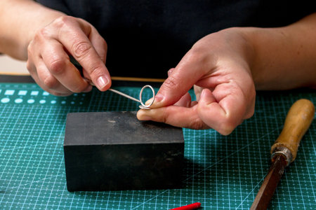 Creating a beautiful silver ring a skilled female artisan in her craft jewelry workshop.