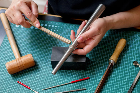 Woman-jeweler meticulously crafting an exquisite silver ring in her crafting jewelry studio.