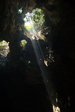 Breathtaking view of hidden cave entrance Illuminated by glowing beam of sunlight rays. Marble...