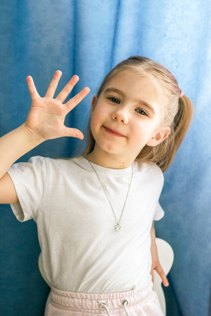Adorable Girl in a White Clothes Waving Hand. Joyful Greeting of Child with a Cheerful Expression.