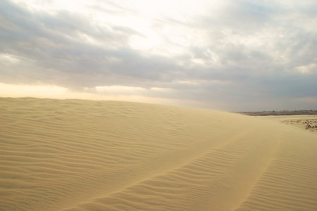 Golden Sand Under a Cloudy Sky A Serene Desert Landscape Experience. Mui Ne, Vietnam, White Dunes.の写真素材
