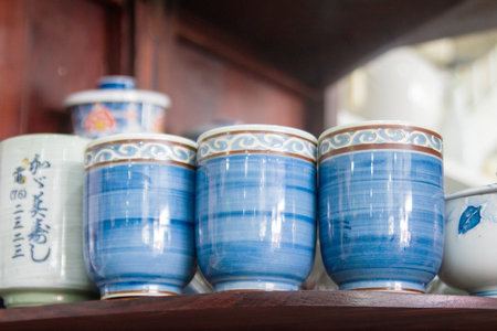 A set of traditional Japanese tea cups with intricate blue patterns on a dark wooden shelf.の写真素材