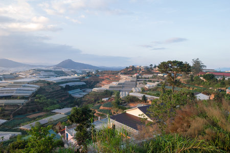 Picturesque Valley Landscape with Greenhouses and Distant Mountain Peaks at Sunrise. Dalat, Vietnam.の写真素材