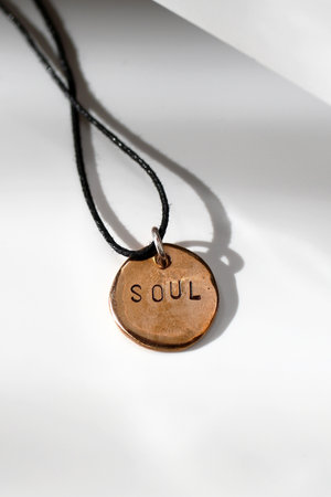 Bronze Soulful Pendant on White Backdrop in Sunlight. A Modern Fashion Handmade Accessory Image.