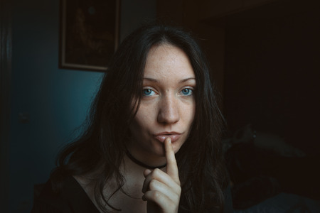 blue-eyed girl with a finger on her lips asking for silenceの写真素材