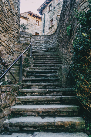 Stone ascendant stairs in a medieval village between stone walls with some houses in the background.の写真素材
