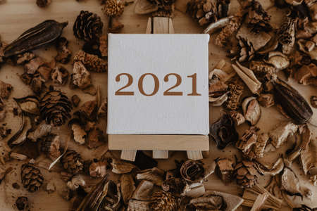 2021 written in brown on the canvas of an easel with dried brown fruits and flowers around it.の写真素材