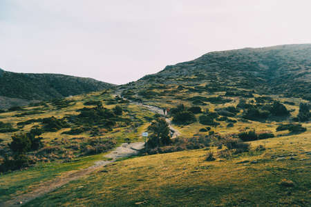 View of some hikers walking up a mountain by a pathの写真素材