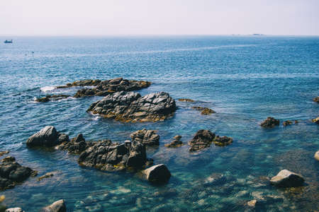 Seascape with views of the horizon with some steep rocks and crystalline blue watersの写真素材