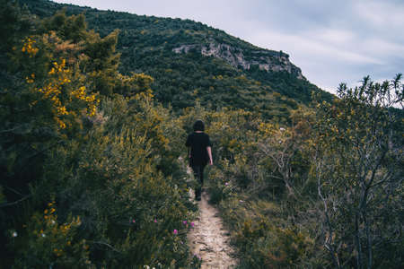 A girl hiker behind her back walking on a mountain path in natureの写真素材