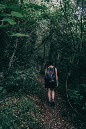 girl walking along a small path that goes into the forest of sadernesの写真素材