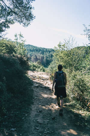 woman walking along a small path in the mountainの写真素材