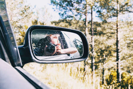 Selfie of a girl in the rear view of the car while the car is running. The girl wears her hair tied...