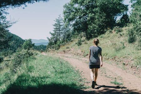 Girl walking along a small path in the mountain of Spain. On a sunny summer dayの写真素材
