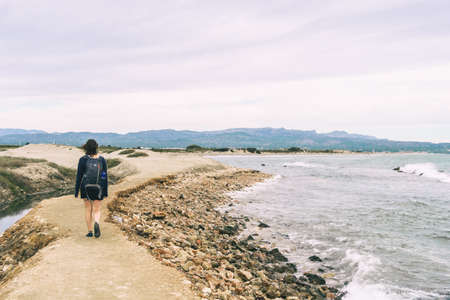 girl strolling on the shore of the beach on a cloudy summer dayの写真素材