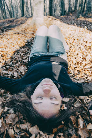 woman enjoying autumn and catching falling yellow leavesの写真素材