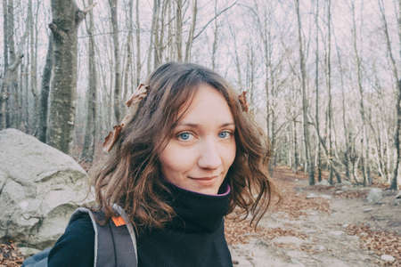 woman enjoying autumn and catching falling yellow leaves