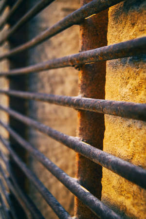 window with a rusty grille with a wrought iron pattern