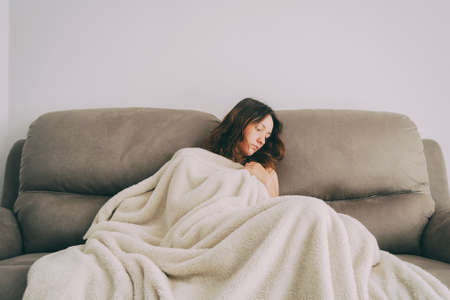 girl covered with a blanket and looking to the side pensivelyの写真素材