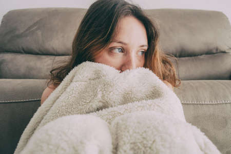 girl covered with a blanket and looking to the side pensivelyの写真素材