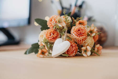 wooden table with a bouquet of flowers and a white heart and bokeh lights around it.の写真素材