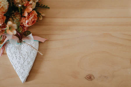 wooden table with a bouquet of flowers and a white heartの写真素材