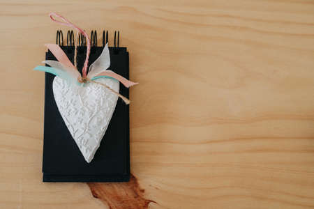 notebook with black sheets with copy space, on a wooden table with a white heart.の写真素材