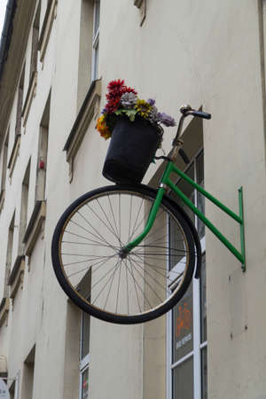 Riga, Riga district / Latvia - November 22, 2019: the front part of the bicycle with a basket of flowers sticks out of the wall - project of a bicycle workshop, creative on the streets of Rigaのeditorial素材
