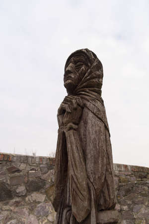Mukachevo, Mukachevo district, Transcarpathian region / Ukraine - January 24, 2018: wooden sculpture of a grieving elderly woman on the territory of Palanok castle in Mukachevoのeditorial素材