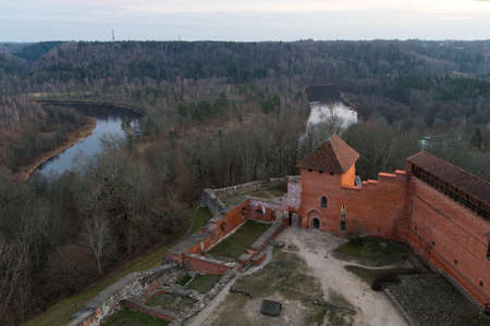Preserved and recreated parts of medieval Turaida Castle (Treiden Castle) on the background of the Gauja River and forest and park landscapes in winter, Latviaのeditorial素材