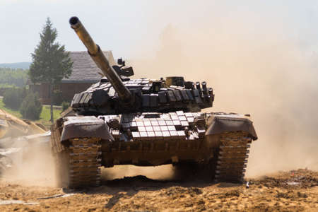 A tank drives through a village, raising clouds of smoke and dust around itselfのeditorial素材