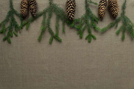 Christmas background in natural folk style: decor of Christmas tree branches and cones on linen art canvasの写真素材