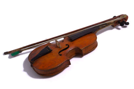 Unusual vintage antique rustic homemade brown violin with a fiddle-bow lies on a white surfaceの写真素材
