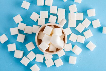 coffee cup full of sugar cubes isolated on pastel blue background, hidden sugar in sweet drinks, diabetes risk, studio shot, top view, flat layの写真素材