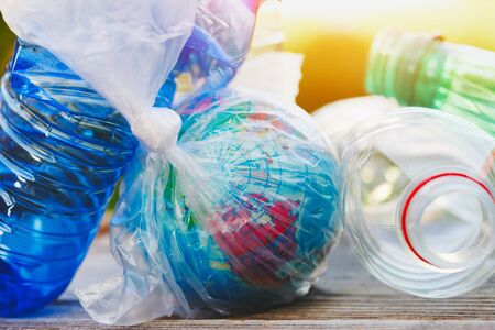 environment pollution concept, planet earth wrapped in plastic bag and used plastic bottlesの写真素材