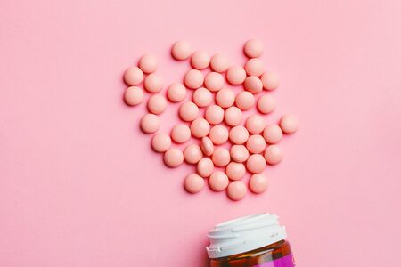 heap of pink pharmaceutical tablets, medicine pills and bottle on pastel background, top view, copy space, flat layoutの写真素材