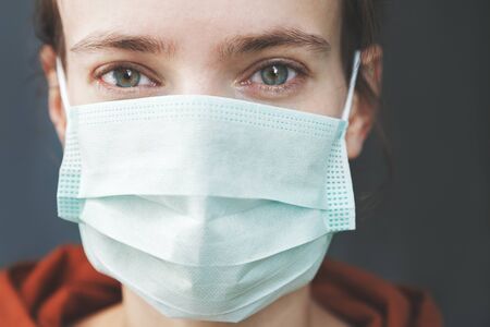 close up young woman wearing surgical mask because of viruses and air pollution in the city