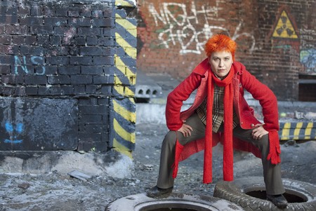 Red-haired woman stands on the old tires in active and strong pose. She is stright looking to the cameraの写真素材