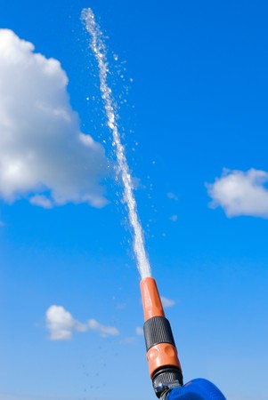 Hose with stream of water flowing in the skyの写真素材