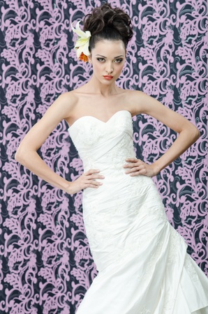 Young adult bride in white wedding dress posing over magenta wall  の写真素材