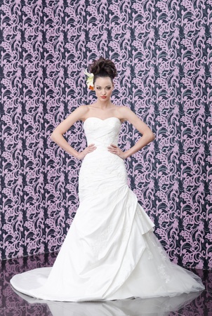 Young adult bride in white wedding dress posing over magenta wall の写真素材