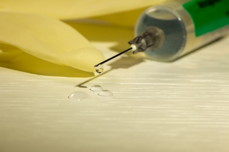 a syringe with a drug dropping from the needleの写真素材