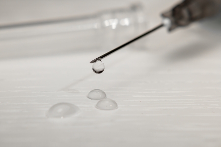 a syringe with a drug dropping from the needleの写真素材