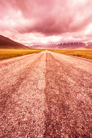 dark clouds on the road between the fieldsの写真素材