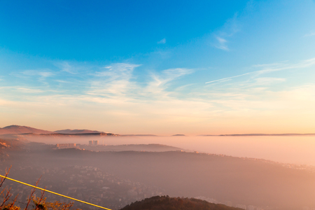 Sun goes down on the city of Trieste while the bay is covered by fogの写真素材
