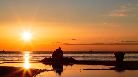 a young couple watching a beautiful sunset on the sea of Triesteの写真素材