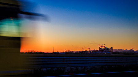 sunset on the highway in front of an industryの写真素材