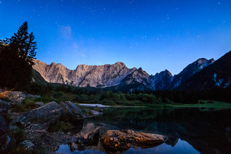 The sun goes down in front of Mount Mangart in the italian alpsの写真素材