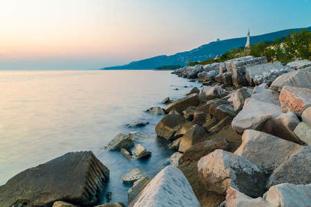 sunset at the beach below the lighthouse of Trieste, Friuli Venezia-Giulia, Italyの写真素材