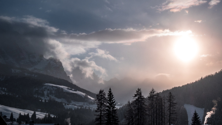 Sun goes down on an alpine valley in italy during a snowy winterの写真素材